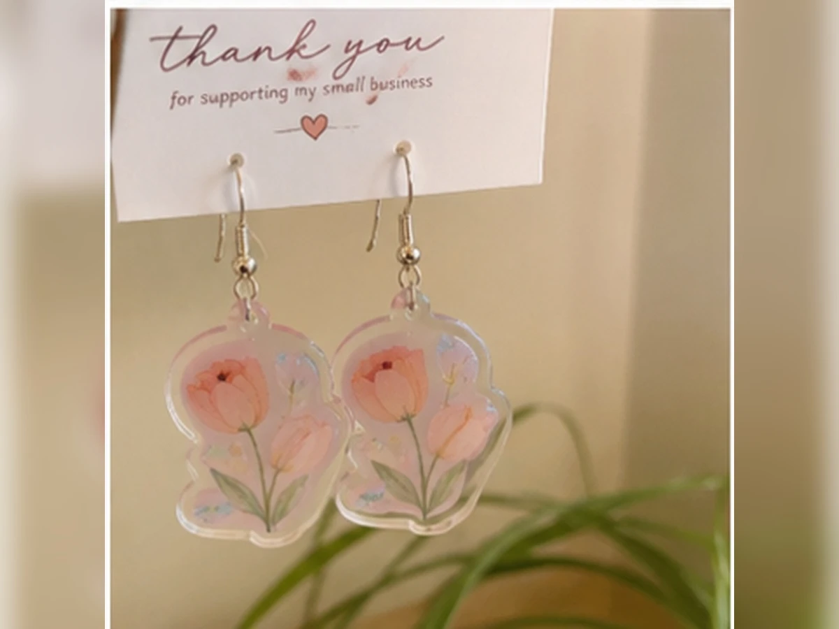 UV printed floral acrylic earrings displayed on a wooden vanity table