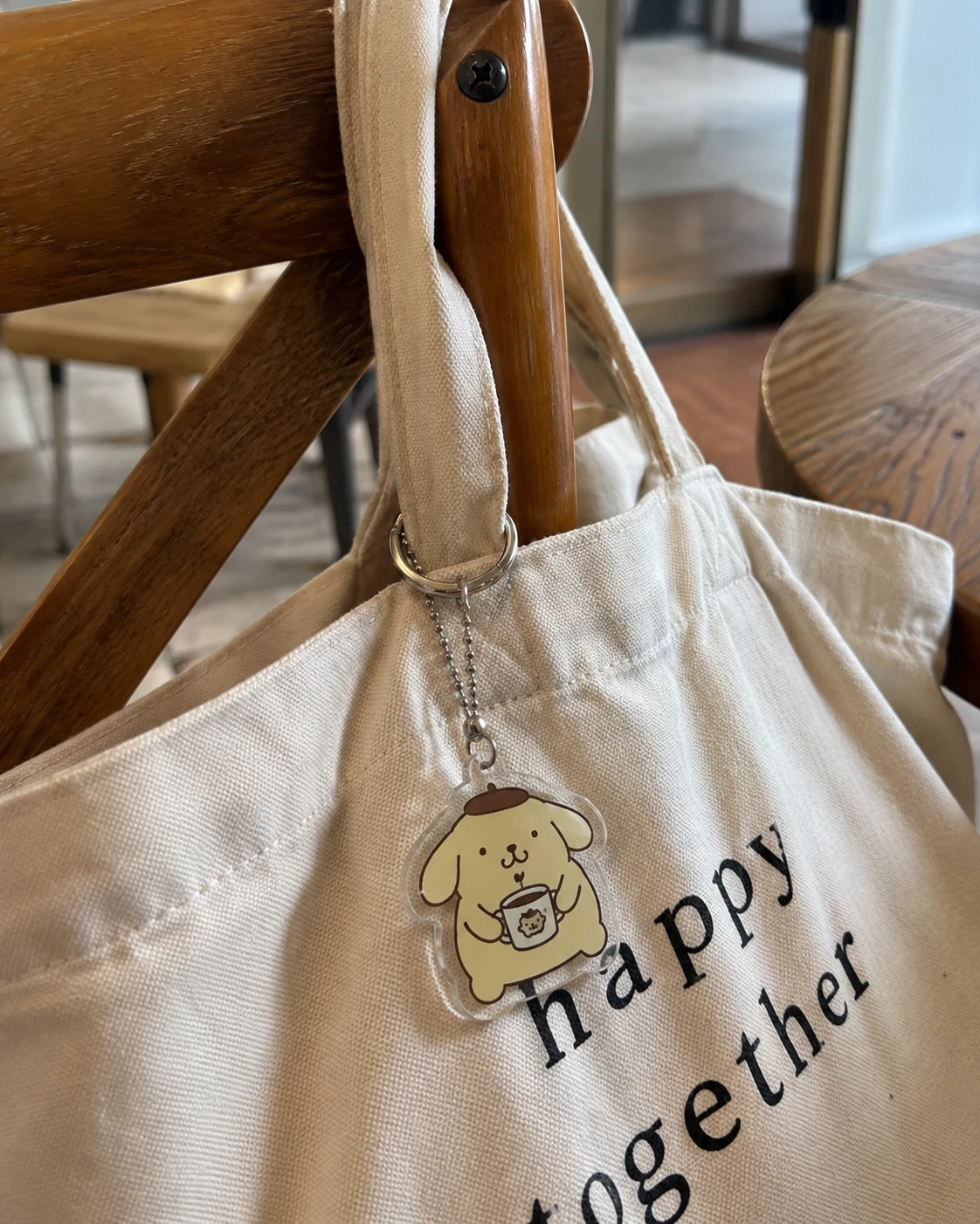 Cute UV printed acrylic character keychain hanging from a canvas tote bag