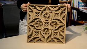 person holding a square wooden slab with an intricate engraving