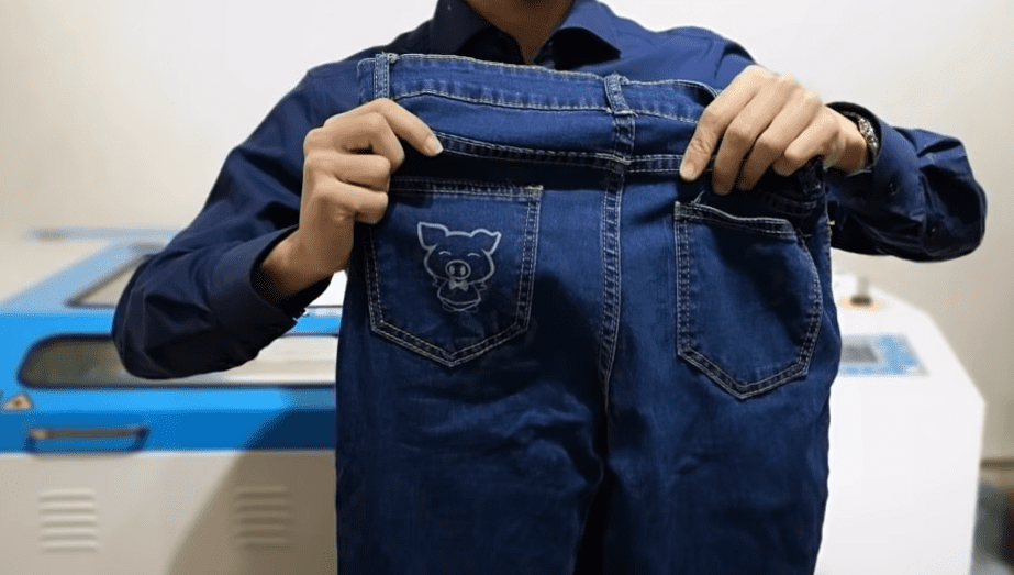 person holding a pair of jeans with a pig design on the back pocket