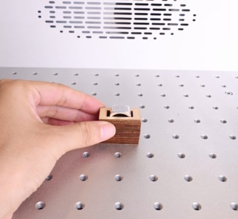 a pictureof putting a silver ring onto the work table of the laser machine.